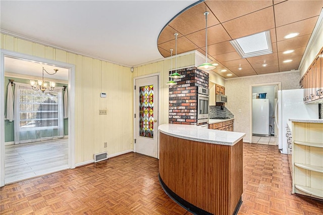 kitchen with stainless steel appliances, a chandelier, kitchen peninsula, and light parquet flooring