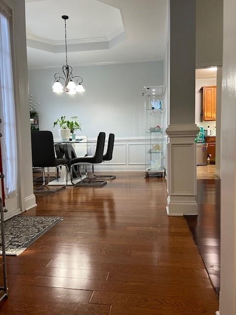 dining space with crown molding, a tray ceiling, and dark wood-type flooring