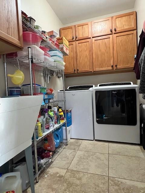 laundry area featuring cabinets, light tile patterned floors, and washer and dryer