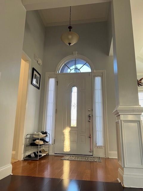 foyer entrance featuring a high ceiling, dark hardwood / wood-style floors, and decorative columns