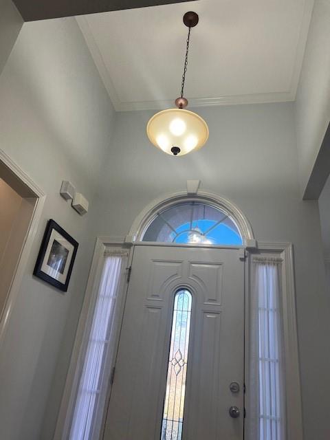 entryway featuring crown molding and a towering ceiling