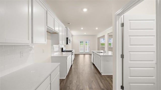 kitchen with sink, white cabinetry, appliances with stainless steel finishes, dark hardwood / wood-style floors, and decorative backsplash