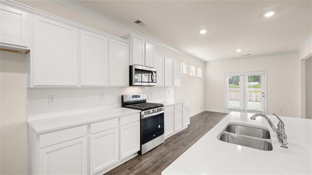 kitchen with dark hardwood / wood-style floors, white cabinetry, sink, backsplash, and stainless steel appliances