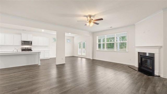 unfurnished living room with dark wood-type flooring, ceiling fan, crown molding, and sink