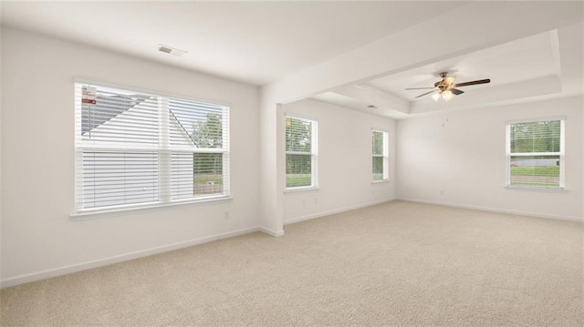 carpeted empty room featuring ceiling fan and a raised ceiling