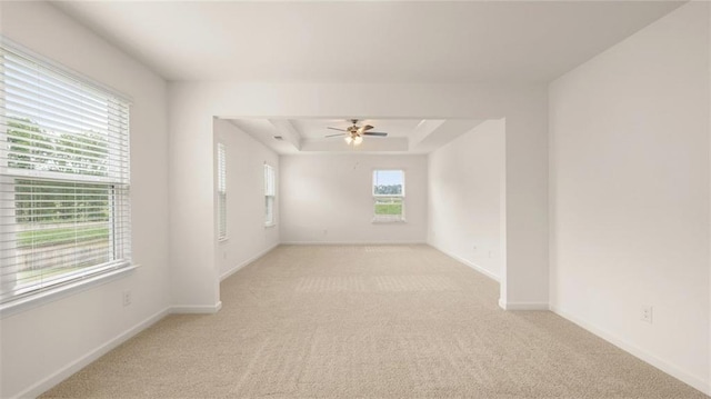 carpeted empty room featuring ceiling fan and a raised ceiling