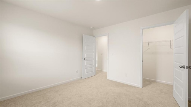 unfurnished bedroom with light colored carpet, a spacious closet, and a closet