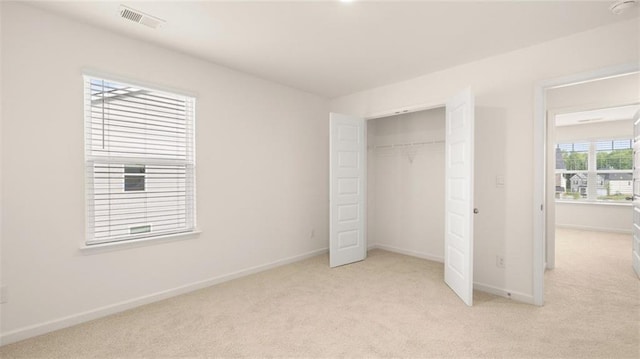 unfurnished bedroom with light colored carpet and a closet