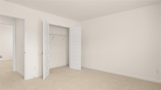 unfurnished bedroom with light colored carpet and a closet