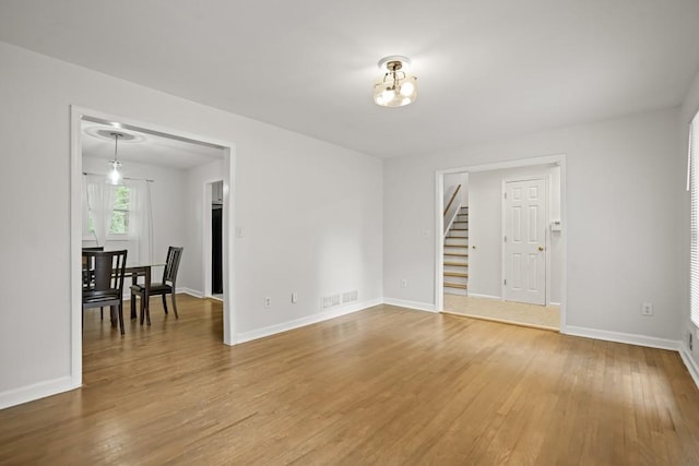 spare room with a notable chandelier and wood-type flooring