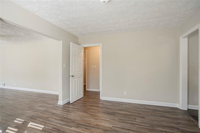 unfurnished room with baseboards, a textured ceiling, and dark wood finished floors