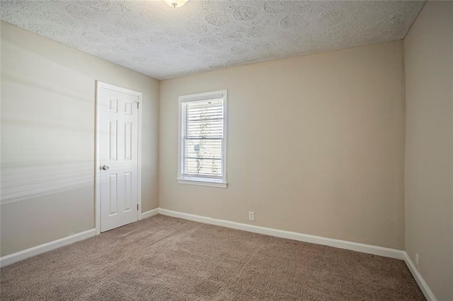 carpeted spare room with baseboards and a textured ceiling