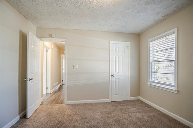 unfurnished bedroom featuring baseboards, a textured ceiling, and carpet flooring