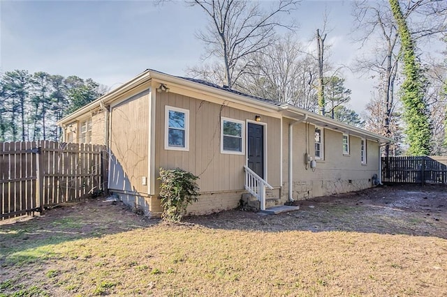 view of side of home with crawl space, a yard, entry steps, and a fenced backyard