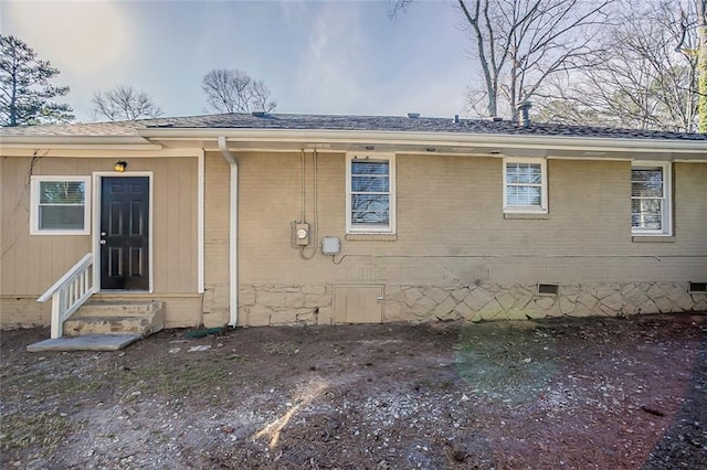 rear view of property featuring crawl space, brick siding, roof with shingles, and entry steps