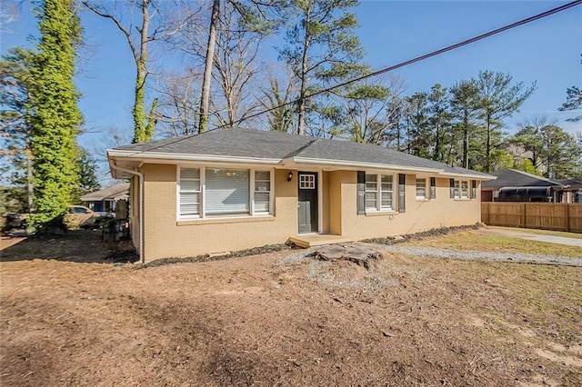 view of front of house featuring brick siding and fence