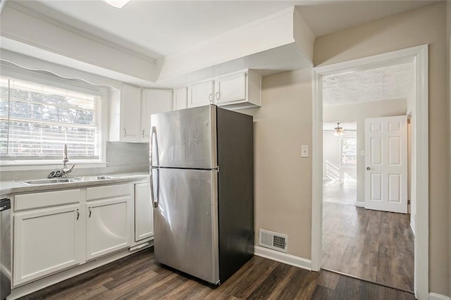 kitchen featuring visible vents, a sink, stainless steel appliances, dark wood-type flooring, and white cabinetry