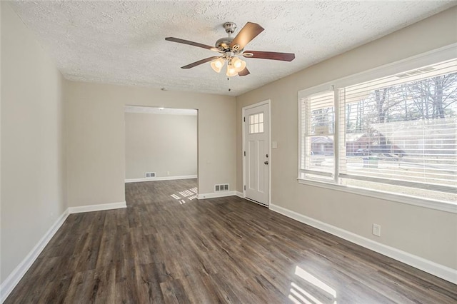 entrance foyer featuring dark wood-style floors, visible vents, a textured ceiling, and baseboards