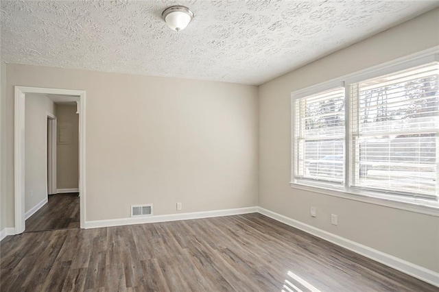 unfurnished room with visible vents, baseboards, a textured ceiling, and wood finished floors