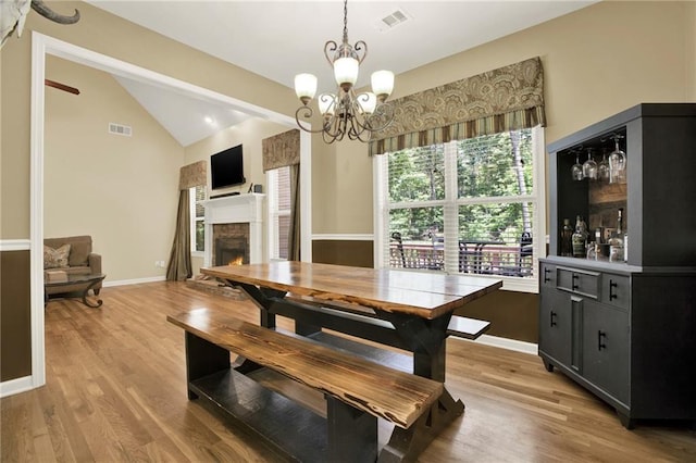 34 Laurel Way NE, White, GA 30184 - dining room with vaulted ceiling, light wood-type flooring, a chandelier, a fireplace, and baseboards