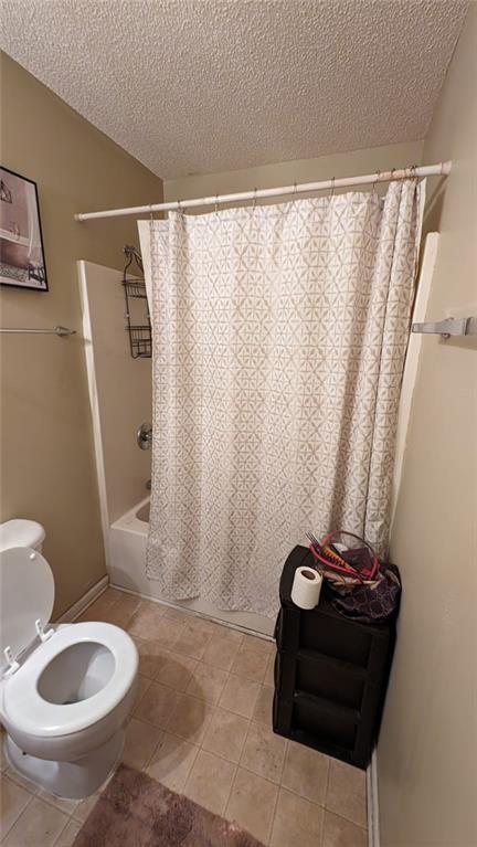 bathroom featuring shower / tub combo with curtain, tile patterned flooring, a textured ceiling, and toilet