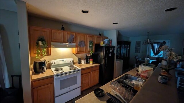 kitchen with pendant lighting, a textured ceiling, black fridge, and white electric range