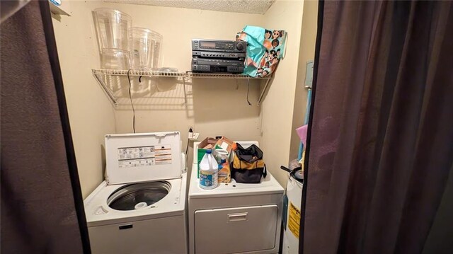 clothes washing area with a textured ceiling and washing machine and dryer