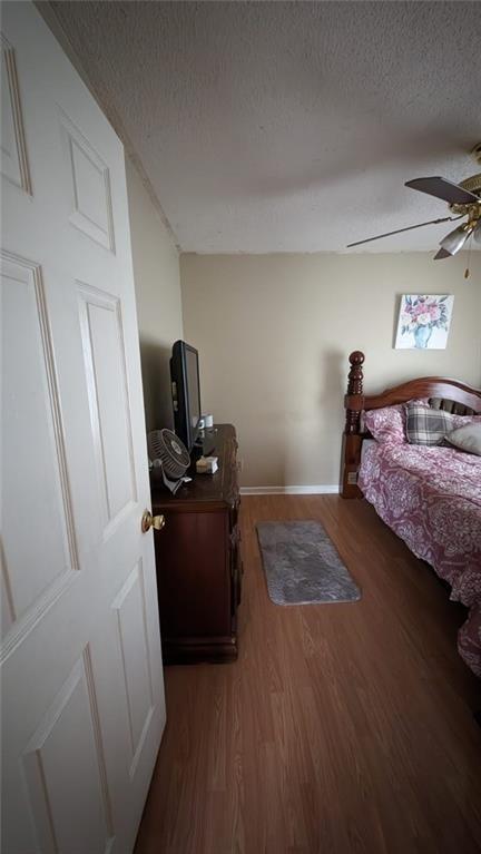 bedroom with ceiling fan, a skylight, dark hardwood / wood-style floors, and a textured ceiling