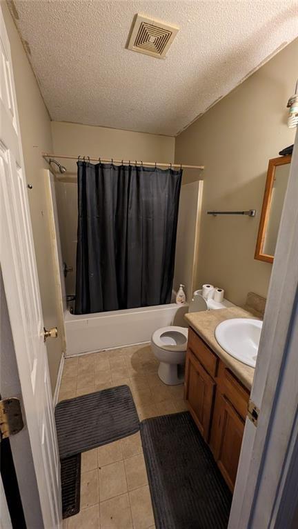 full bathroom featuring shower / bath combo, a textured ceiling, vanity, and toilet