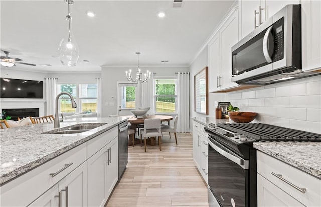 402 Beacon Way, Villa Rica, GA 30180 - kitchen featuring appliances with stainless steel finishes, a sink, crown molding, a lit fireplace, and decorative backsplash