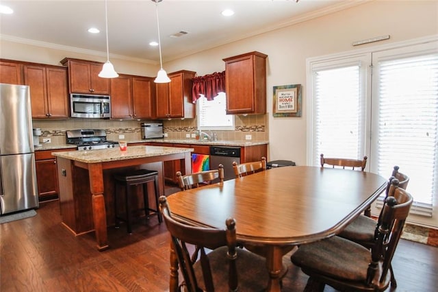 6892 Big Sky Dr, Flowery Branch, GA 30542 - kitchen with appliances with stainless steel finishes, a center island, dark wood-style flooring, tasteful backsplash, and ornamental molding