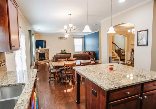 6892 Big Sky Dr, Flowery Branch, GA 30542 - kitchen featuring ornamental molding, ceiling fan, dark wood-style floors, a fireplace, and arched walkways