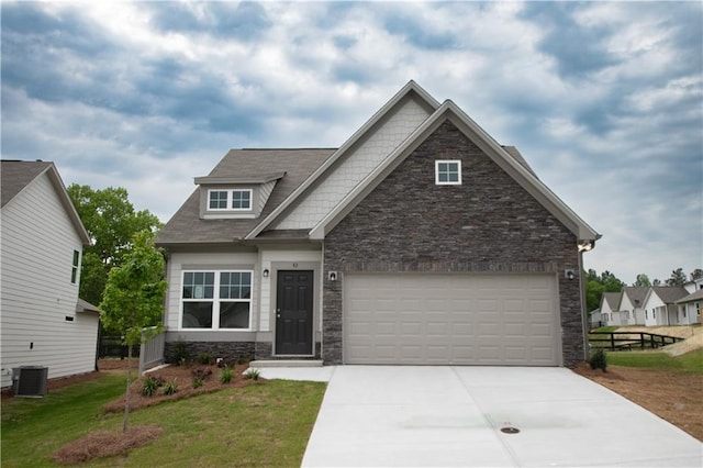 craftsman-style house with central AC unit, a garage, and a front yard