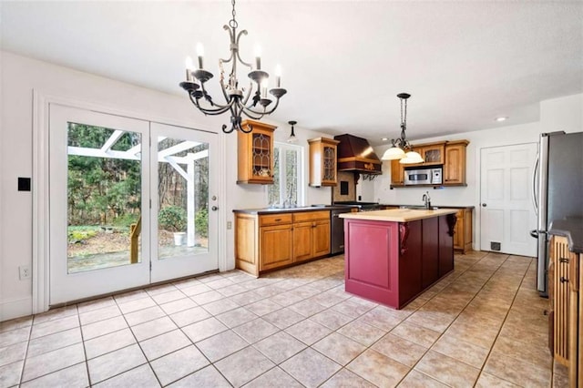 kitchen featuring premium range hood, sink, light tile patterned floors, appliances with stainless steel finishes, and a kitchen island