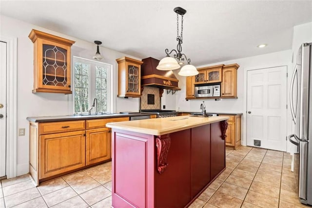 kitchen featuring sink, a center island with sink, light tile patterned floors, appliances with stainless steel finishes, and custom range hood