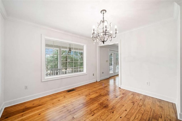 spare room featuring hardwood / wood-style flooring, crown molding, and an inviting chandelier