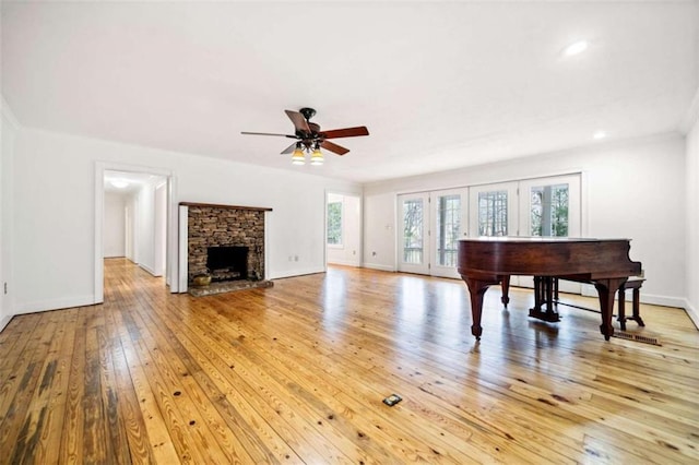 miscellaneous room featuring crown molding, ceiling fan, a fireplace, and light hardwood / wood-style flooring