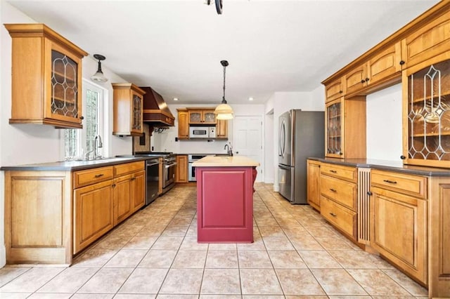 kitchen with appliances with stainless steel finishes, an island with sink, sink, custom exhaust hood, and hanging light fixtures