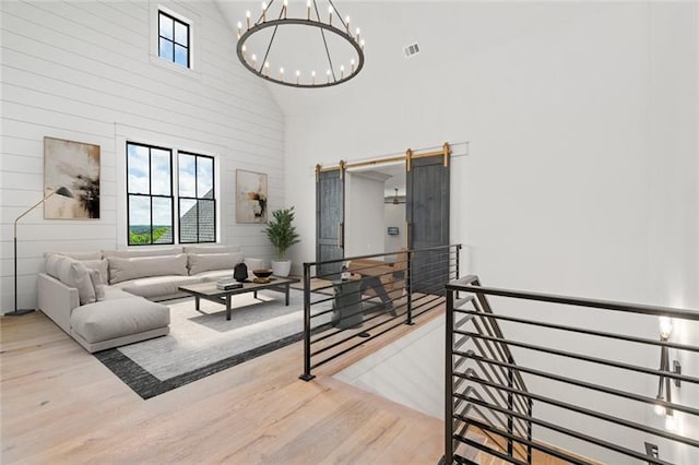 living room with a towering ceiling, a chandelier, and hardwood / wood-style flooring