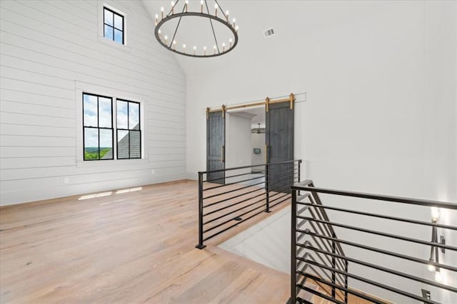 staircase featuring hardwood / wood-style flooring, high vaulted ceiling, and a chandelier