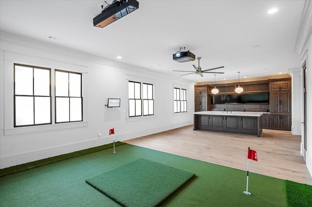 exercise area featuring light wood-type flooring, ceiling fan, and crown molding