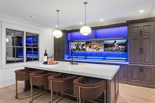 bar with pendant lighting, light hardwood / wood-style floors, crown molding, and sink