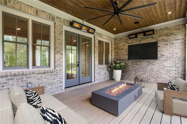 wooden terrace featuring french doors, ceiling fan, and an outdoor living space with a fire pit