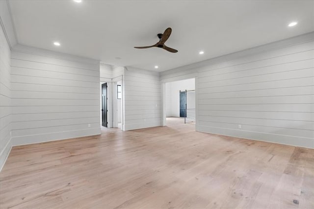 unfurnished living room with light hardwood / wood-style flooring, ceiling fan, and wooden walls