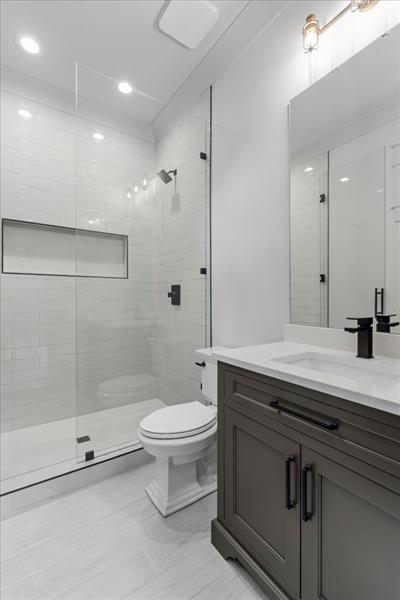 bathroom featuring a tile shower, vanity, and toilet