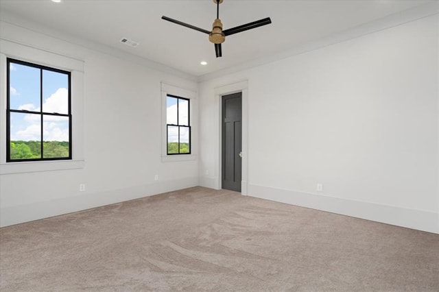 carpeted spare room with ceiling fan, a healthy amount of sunlight, and ornamental molding