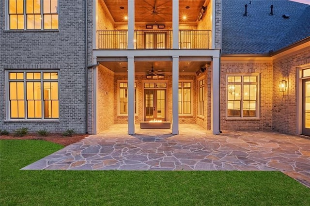 view of exterior entry featuring ceiling fan, a balcony, and a patio