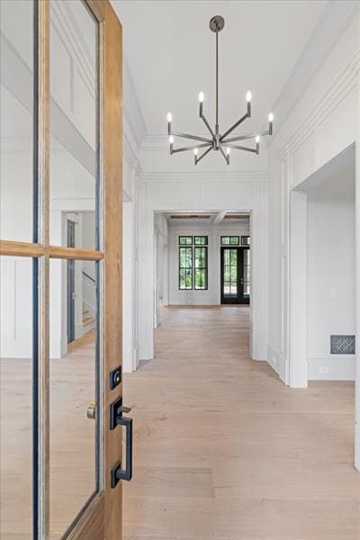 corridor with light hardwood / wood-style flooring and an inviting chandelier