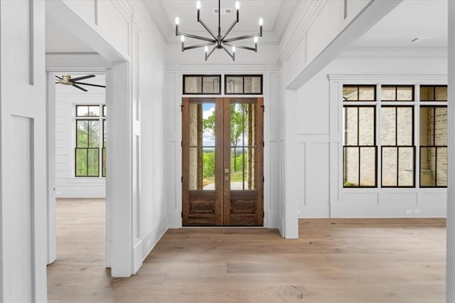 entrance foyer featuring french doors, ceiling fan with notable chandelier, light hardwood / wood-style floors, and crown molding