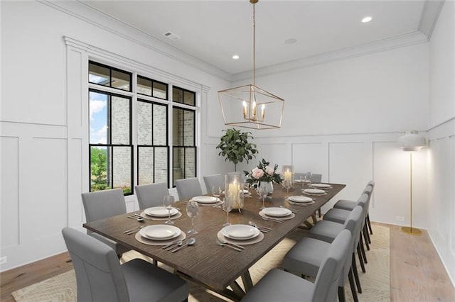 dining room with hardwood / wood-style flooring, an inviting chandelier, and ornamental molding